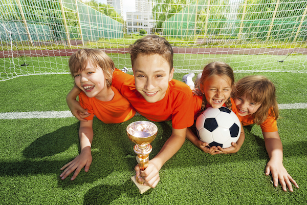 Happy kids laying on grass with golden goblet